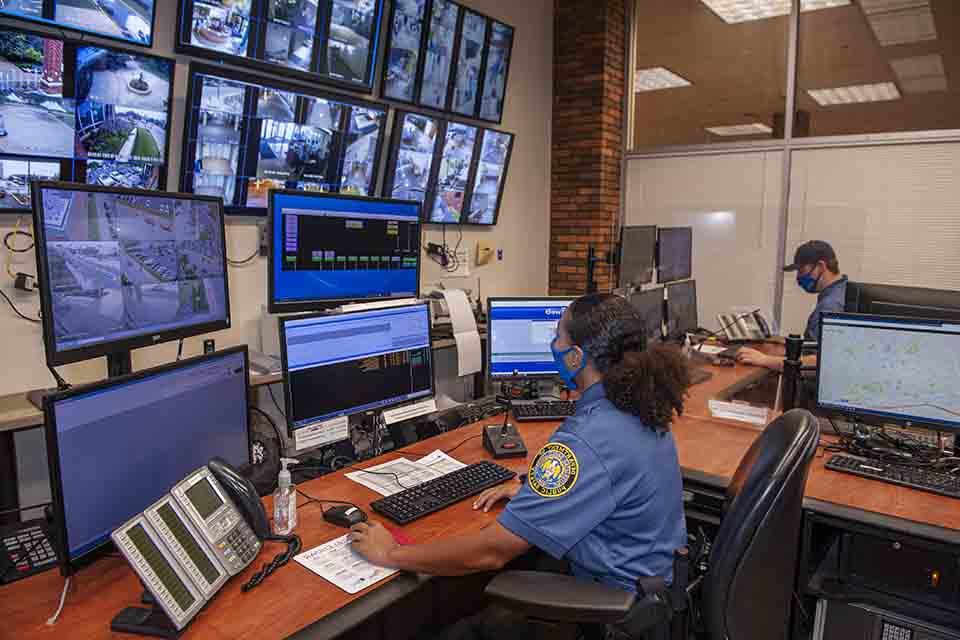 DPS officer sits in front of a bank of monitors and screens.